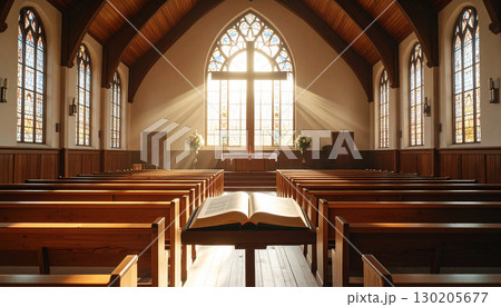 Empty church interior with sunlight streaming through stained glass, wooden pews aligned in symmetry, open Bible with a wooden cross at the altar. Symbol of faith, worship, and Christian spirituality 130205677