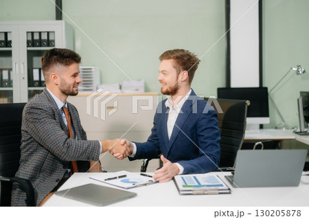 Two office colleagues discuss ideas for a startup project in a modern workspace, using laptops and smartphones 130205878