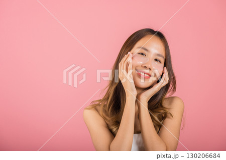 Femininity. Asian beautiful young woman smiling mask cosmetic patches gel under the eyes, Portrait female touching clean skin medical hydrogel eye patch on face, isolated on pink background, skincare 130206684