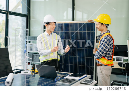 Two Asian engineers collaborate on a solar and wind energy project, discussing innovation and sustainability 130206748