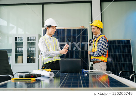 Two Asian engineers collaborate on a solar and wind energy project, discussing innovation and sustainability 130206749