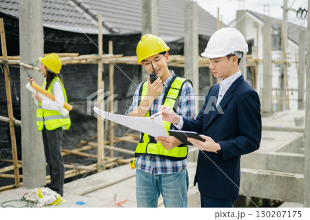 Contractor and architect looking at plan, tablet, laptop and talking about working on big project. Contractor and architect looking at plan, tablet, laptop and talking about working on big project. 130207175