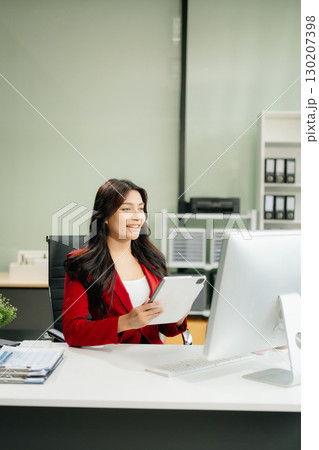 Asian woman using laptop and tablet while sitting at her working place 130207398