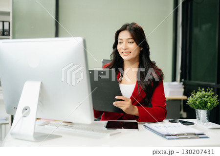 Asian woman using laptop and tablet while sitting at her working place 130207431