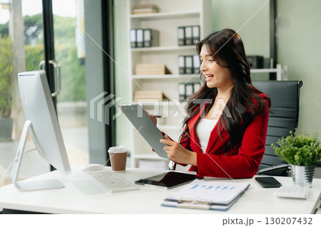 Asian woman using laptop and tablet while sitting at her working place 130207432