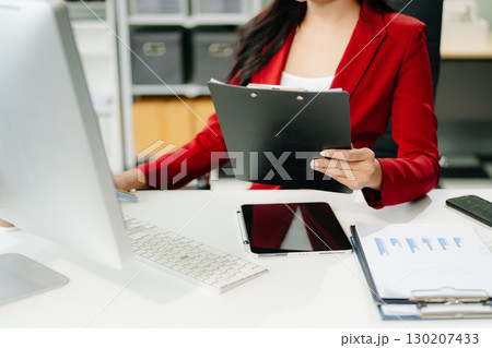 Asian woman using laptop and tablet while sitting at her working place 130207433