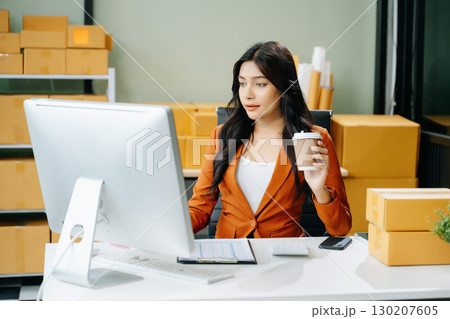 Young business owner woman prepare parcel box and standing check online orders for deliver to customer Young business owner woman prepare parcel box and standing check online orders for deliver to customer 130207605