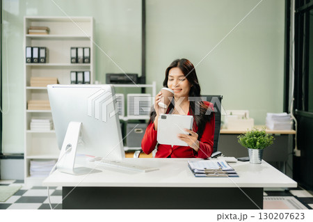 Asian woman using laptop and tablet while sitting at her working place Asian woman using laptop and tablet while sitting at her working place 130207623