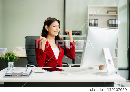 Asian woman using laptop and tablet while sitting at her working place 130207629