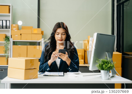 Young business owner woman prepare parcel box and standing check online orders for deliver to customer Young business owner woman prepare parcel box and standing check online orders for deliver to customer 130207669