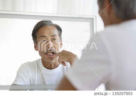 鏡を見て歯茎を気にする60代の男性 130207803