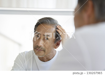 鏡を見て生え際を気にする60代の男性 130207965