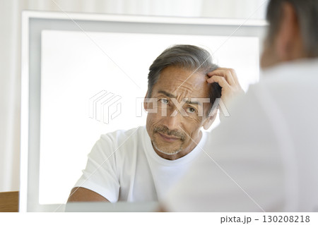 鏡を見て生え際を気にする60代の男性 鏡を見て生え際を気にする60代の男性 130208218