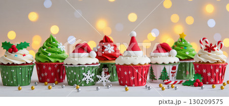 Christmas cupcakes with festive frosting and holiday decorations including Santa hats, snowflakes, candy canes and holly. Colorful holiday treats. 130209575