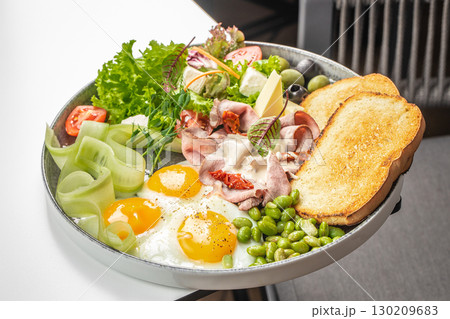 Breakfast plate with fried eggs, toast, ham, cheese, vegetables and fresh salad Breakfast plate with fried eggs, toast, ham, cheese, vegetables and fresh salad 130209683
