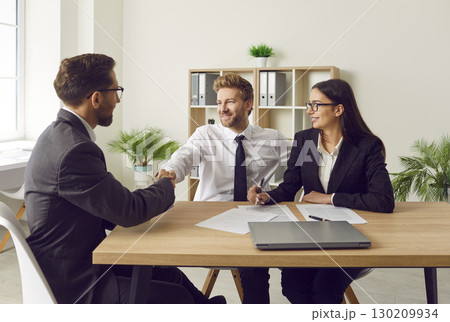 Happy couple signing a contract and shaking hands with business broker man or insurance agent. Happy couple signing a contract and shaking hands with business broker man or insurance agent. 130209934