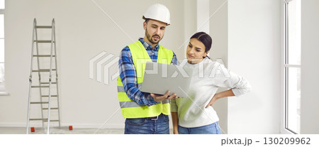 Foreman showing to a young woman design project of apartment renovation on a laptop Foreman showing to a young woman design project of apartment renovation on a laptop 130209962