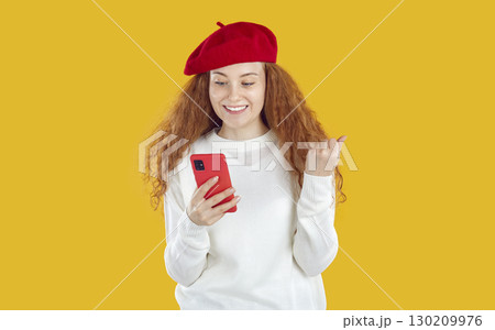 Smiling curly girl looking at smartphone pointing finger on copy space on yellow background. Smiling curly girl looking at smartphone pointing finger on copy space on yellow background. 130209976