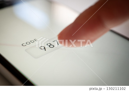 スマホに認証コードを指で入力する写真 (ログイン、ロック解除、二段階認証) 130211102