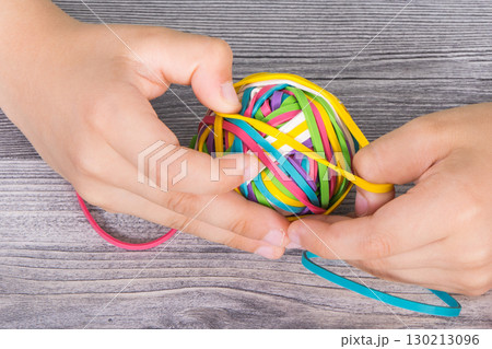 Preschooler hands playing with rubber bands or erasers Preschooler hands playing with rubber bands or erasers 130213096