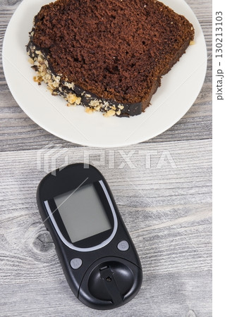 Glucose meter and sweet chocolate cake. Checking sugar level during diabetes 130213103
