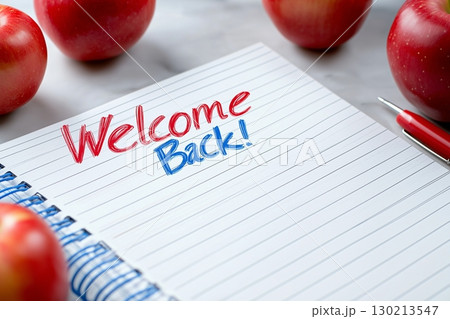 Handwritten Welcome Back on a lined notebook with red and blue ink, surrounded by red apples Handwritten Welcome Back on a lined notebook with red and blue ink, surrounded by red apples 130213547