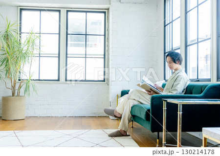 ソファに座って本を読む男性 ソファに座って本を読む男性 130214178