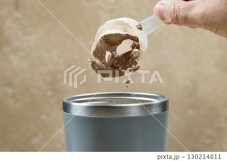 protein powder spills in cup from measure scoop.  whey sports nutrition. dry mixture 130214811