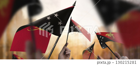 Papua New Guinea flags in their hands on a blurred urban background 130215281