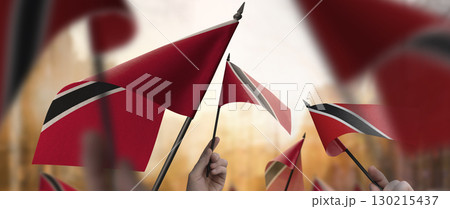 Trinidad and Tobago flags in their hands on a blurred urban background 130215437