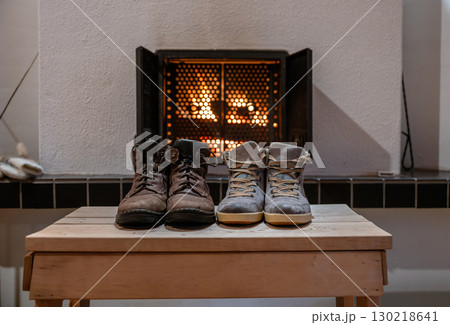 Pair of winter boots drying in front of fireplace indoors cozy home atmosphere 130218641