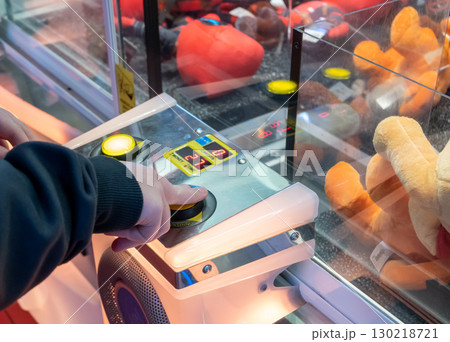 Hand of little boy press on the button of toy machine and looking through glass to the much toys. 130218721