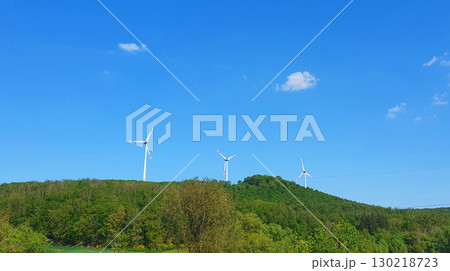 Three white windmills with green field and blue sky. Wind turbine for alternative green energy in Europe. Three white windmills with green field and blue sky. Wind turbine for alternative green energy in Europe. 130218723