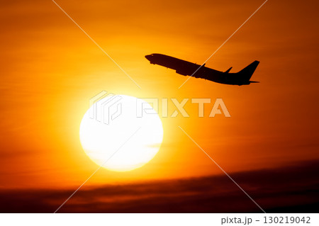 美しい夕日・空・雲を背景にした飛行機 130219042