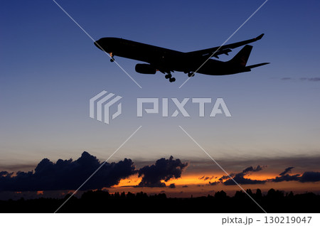 美しい夕日・空・雲を背景にした飛行機 130219047