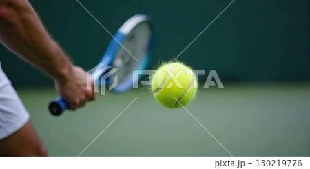 A tennis racket swings mid-action, with the ball in sharp focus, capturing the intensity and speed of the game. 130219776