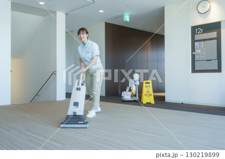オフィスビルの床に掃除機をかける若い女性清掃員　撮影協力：学校法人電波学園 東京電子専門学校 130219899