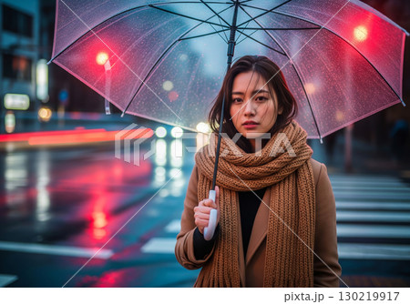 茶色のコートとマフラーを巻いた女性が傘をさす、雨の夜のポートレート 茶色のコートとマフラーを巻いた女性が傘をさす、雨の夜のポートレート 130219917