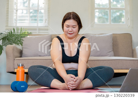 Wellness and mindfulness plus-size woman practicing yoga at home. 130220339