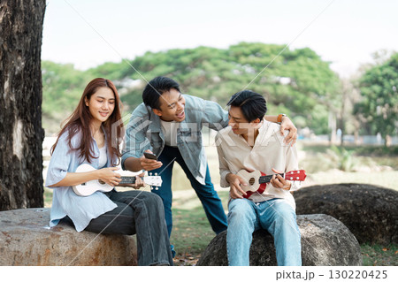 Friends enjoying a fun music session with ukuleles in a sunny park Friends enjoying a fun music session with ukuleles in a sunny park 130220425