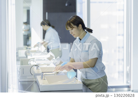 オフィスビルの洗面所の洗面台を拭く若い女性清掃員　撮影協力：学校法人電波学園 東京電子専門学校 130220828