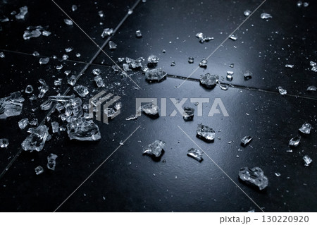 Shattered glass on black tiled floor with reflective surface in low light Shattered glass on black tiled floor with reflective surface in low light 130220920