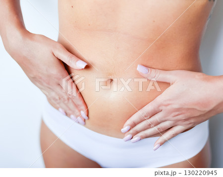 Close up of female caucasian young adult in white underwear touching flat stomach Close up of female caucasian young adult in white underwear touching flat stomach 130220945