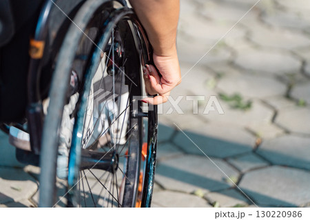 Person in a wheelchair navigating outdoor pathways with determination and strength Person in a wheelchair navigating outdoor pathways with determination and strength 130220986