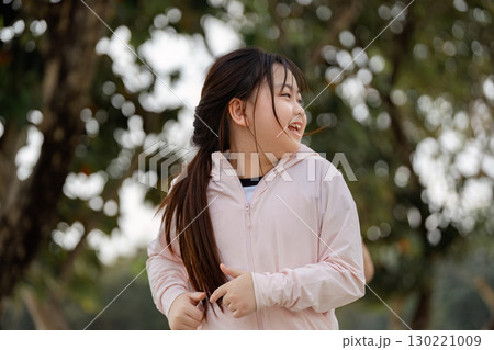 Joyful daughter exercising outdoors, smiling during her active playtime surrounded by nature Joyful daughter exercising outdoors, smiling during her active playtime surrounded by nature 130221009