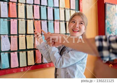 Young woman enthusiastically explaining traditional calendar concepts while guiding a friend in a vibrant cultural setting 130221125