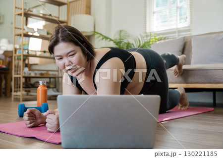 Plus-size woman strength training at home, lifting dumbbell to enhance her wellness and fitness routine 130221185