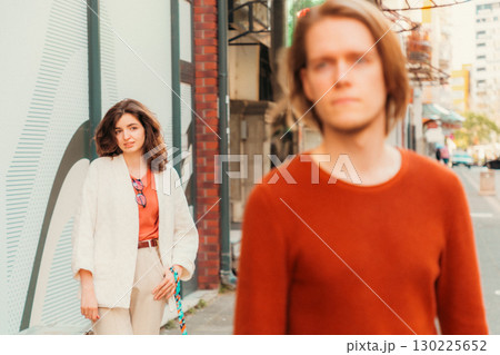 Young Caucasian woman smiling and looks at blurred handsome young man passing by on street. Psychology of relationship Young Caucasian woman smiling and looks at blurred handsome young man passing by on street. Psychology of relationship 130225652