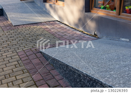 A woven path of brick and stone creates a seamless transition in a bustling urban area, reflecting sunlight near a display of colorful toys 130226393