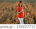 Woman meditating while sitting cross-legged in a golden wheat field during sunset hours for a sense of peace and tranquility 130227713
